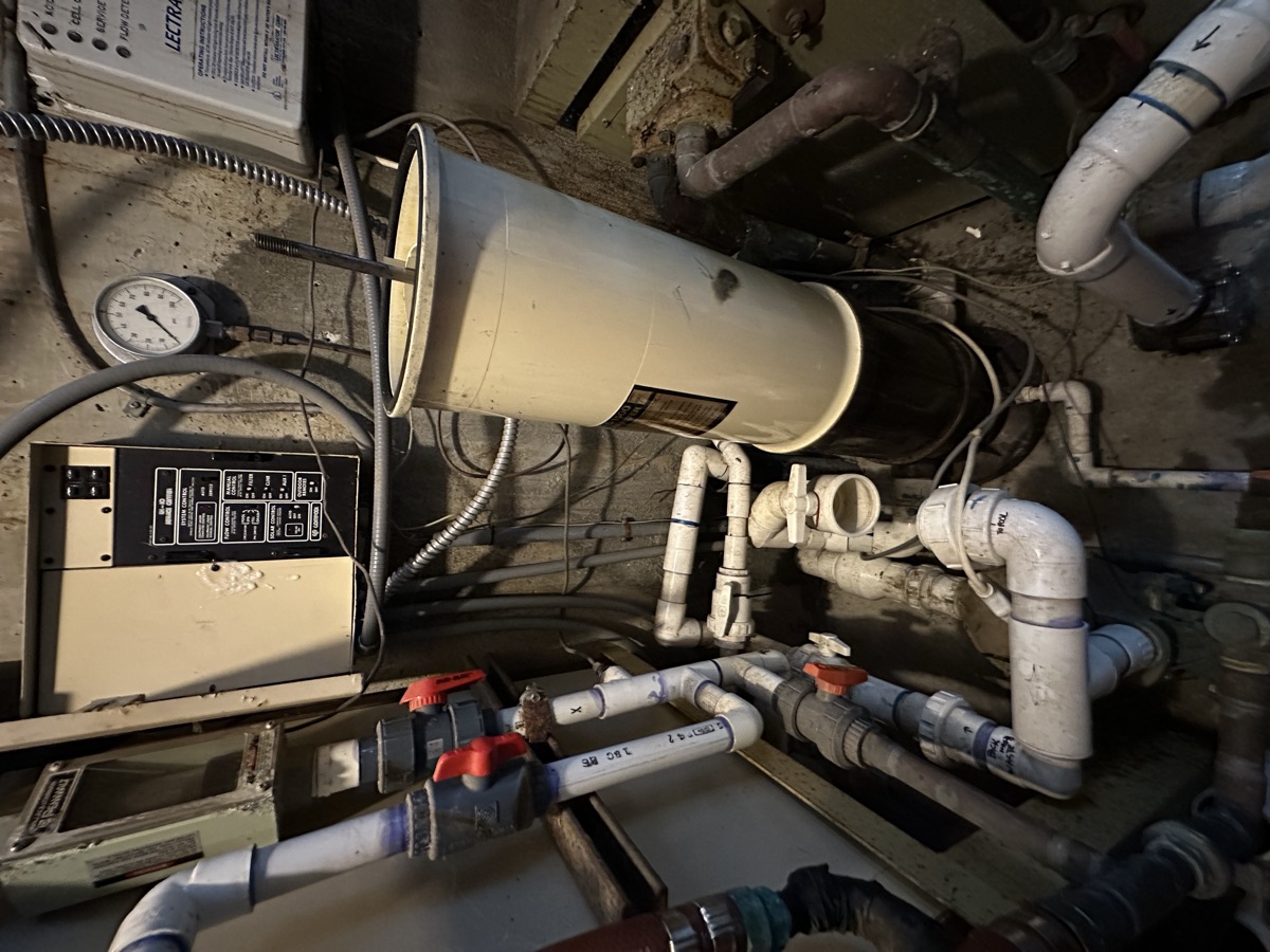 Aging pool equipment room with corroded plumbing found during an ASA Pools and Hot Tubs inspection in Seattle